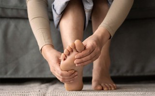 Frau hält schmerzenden Fuß mit beiden Händen