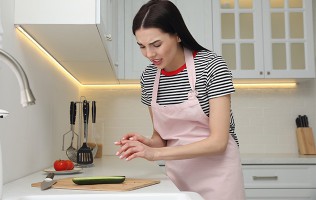 Frau in der Küche mit einer Schnittwunde am Finger