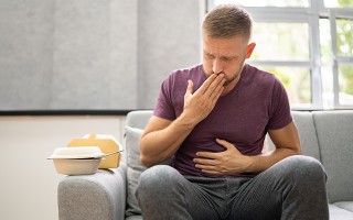 Mann mit Übelkeit und Sodbrennen nach dem Essen