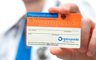 Eine Person haelt einen deutschen Organspendeausweis in die Kamera.