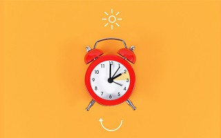 Roter Wecker vor gelbem Hintergrund als Symbol für Zeitumstellung.