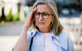 Frau hält sich wegen Kopfschmerzen die Stirn